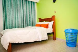 a bedroom with a bed with white sheets and orange pillows at Sunninghills in Nairobi