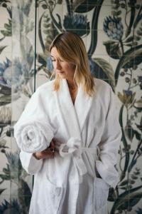 a woman in a white robe standing in front of a wall at Boutique Hotel Pachers in Bressanone