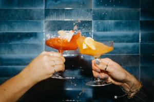 a person holding two martini glasses in their hands at Boutique Hotel Pachers in Bressanone