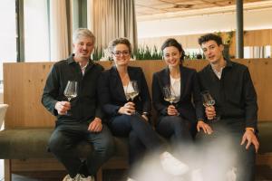a group of people sitting on a bench holding wine glasses at Boutique Hotel Pachers in Bressanone