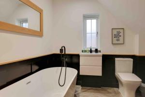 a bathroom with a white tub and a toilet at Kestrel Gardens Five Bedroom Homes in Great Dunmow +45 photos
