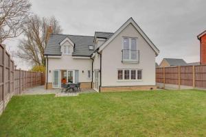 a white house with a fence in a yard at Kestrel Gardens Five Bedroom Homes in Great Dunmow