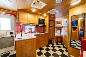 uma cozinha com armários de madeira e um piso em xadrez em Darling Daisy Retro RV Adventure em El Cajon