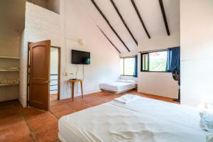 a bedroom with a white bed and a tv at Casa Matiz - Vistas increíbles cerca de Anapoima in Apulo +21 photos