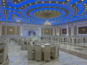 a ballroom with white tables and chairs and a blue ceiling at Theranda Hotel in Prizren