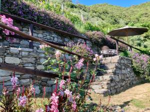 a stone wall with an umbrella and flowers at Villa Pietrafiore in Monterosso al Mare