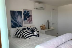 a white bedroom with a bed with three pillows at Arraial | Apartamento com 3 suítes e Vista Mar in Arraial do Cabo +50 photos