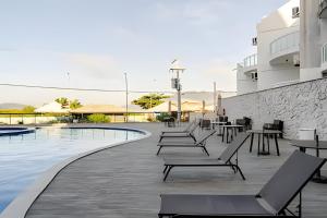 a row of lounge chairs next to a swimming pool at Arraial | Apartamento com 3 suítes e Vista Mar in Arraial do Cabo