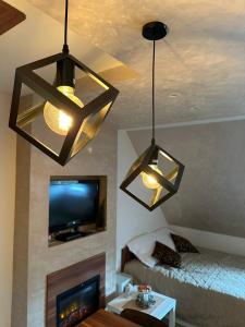 a living room with two chandeliers and a tv at Apartmani Iva Kop Konaci in Kopaonik