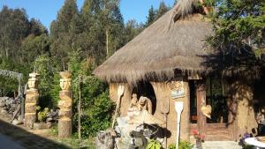a small hut with a thatch roof and some flowers at Cabañas Rukas Licantén in Licantén