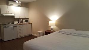 sypialnia z łóżkiem oraz kuchnia z kuchenką mikrofalową w obiekcie Duvernay Studios and Suites w mieście Gatineau