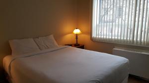 1 dormitorio con cama blanca y ventana en Duvernay Studios and Suites, en Gatineau