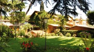 a green yard with a house and a street light at Hotel La Locanda Dei Ciocca in Grottaferrata