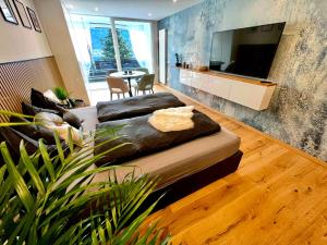 a living room with a couch and a flat screen tv at See-Apartment AURA am Fuße der Gerlitzen Alpe und Ufer des Ossiacher Sees - mit privatem Seezugang & Hallenbad in Steindorf am Ossiacher See