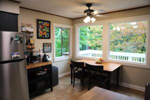 a kitchen with a table and a refrigerator and windows at Mountain Mangrove, A Quiet Mountain Retreat in Lake Toxaway