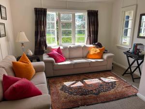 a living room with a couch with colorful pillows at Hawkesbury Cottage in Clive