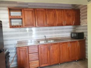 a kitchen with wooden cabinets and a sink at Reyahapartment in Entebbe
