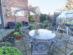 a table and chairs in a garden with a greenhouse at Lavender Cottage in Louth
