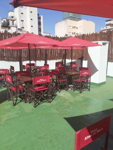 a group of tables and chairs with red umbrellas at Hotel Alma di Mare MDP in Mar del Plata