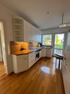 a kitchen with white cabinets and a wooden floor at Stuckenberger Aparthotel in Herford
