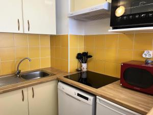 a kitchen with a sink and a red microwave at Résidence Hauts De Peyragudes Mp - T3/8pers -HAUT DE PEYRAGUDES A15- Peyresourde MAE-7491 in Germ
