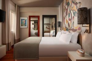 Un dormitorio con una gran cama blanca y un espejo. en Avani Alonso Martinez, en Madrid