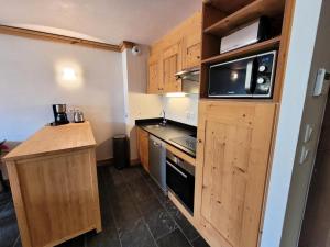 eine kleine Küche mit Holzschränken und einer Mikrowelle in der Unterkunft Résidence Le Criterium - Résidence Le Critérium 3Chalet E Appartement 4 MAE-7721 in Lanslebourg-Mont-Cenis