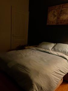 an unmade bed in a dark room with a door at Nid des lumières in Bellegarde-sur-Valserine