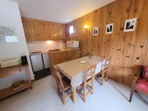 kuchnia ze stołem i krzesłami oraz drewnianymi ścianami w obiekcie Résidence Trolle-soldanelle - Appartement 4 personnes fonctionnel MAE-7811 w mieście Bonneval-sur-Arc