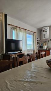 Una sala de estar con un televisor y una mesa y sillas. en Casa planta alta 2 dormitorios, en Valle Hermoso