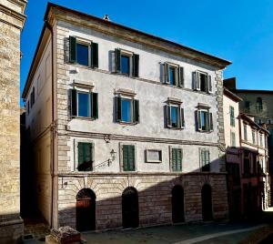 a large white building with green shuttered windows at Palazzo Palloni Boutique Apartment in Sorano