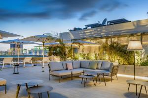 a patio with a couch and tables and umbrellas at AC Hotel by Marriott Tenerife in Santa Cruz de Tenerife