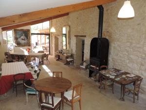 a room with tables and chairs and a wood stove at Le Jas de Péguier in Châteauneuf-Val-Saint-Donat