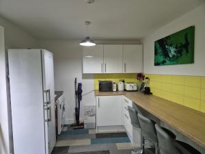 a kitchen with white cabinets and a white refrigerator at The Hyde House - En Suite Rooms in Hyde