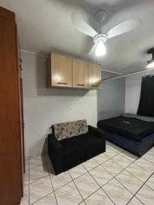 a living room with a bed and a couch at Kit Net Santa Cruz in Praia Grande