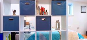 a book shelf with blue boxes and books on it at Suffolk Cosy Corner with free parking, 10min walking to town centre in Bury Saint Edmunds