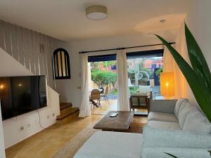a living room with a couch and a tv at Meloneras Garden Bungalow in Meloneras