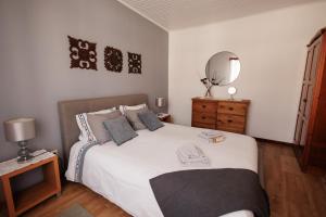 a bedroom with a large white bed with a mirror at Casa da Courela in Nordeste