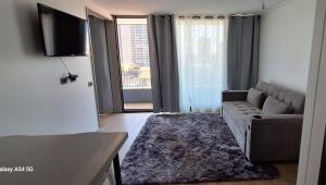 Una sala de estar con un sofá y un televisor de pantalla plana. en Edificio o2, en Santiago