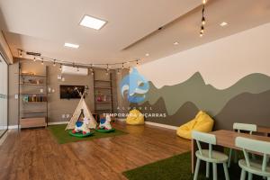 a childrens room with a table and chairs and a play area at Aptos Pé na Areia Vista Mar Condomínio Resort Completo com Piscina borda Infinita, Beach Tennis, Academia, Sala de Jogos, Brinquedoteca, Playground e Portaria 24H 3 Quartos com Ar-Condicionado, Churrasqueira Privativa Reserve Agora e Viva essa Experiência in Piçarras