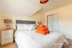 a bedroom with a large bed with an orange towel on it at Violetta Hemsby - Holiday home with Games Room in Hemsby