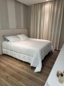 una camera da letto con un letto con lenzuola bianche e una finestra di Cobertura magnífica frente mar a Florianópolis