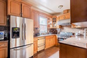 a kitchen with wooden cabinets and a stainless steel refrigerator at Sweet Home - Zoller Stays in Long Island City