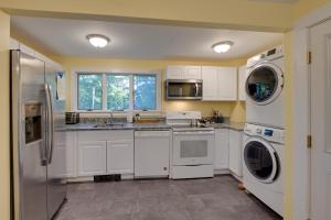 una cucina con mobili bianchi, lavatrice e asciugatrice di Walk to Sorrento Town Dock Pet-Friendly Apartment a Sorrento