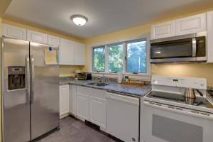 una cucina con armadi bianchi e frigorifero in acciaio inossidabile di Walk to Sorrento Town Dock Pet-Friendly Apartment a Sorrento