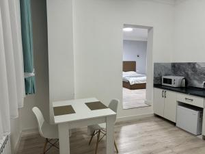 a white kitchen with a table and a bedroom at Жилой Комплекс Акжайык in Astana