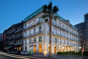 a palm tree in front of a white building at AC Hotel Palacio Universal by Marriott in Vigo