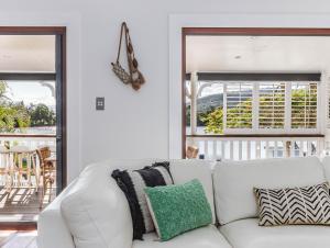 a white couch in a living room with two windows at Riviera Palms in Tumbulgum