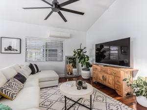 a living room with a white couch and a flat screen tv at Riviera Palms in Tumbulgum
