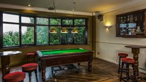 a billiard room with a pool table and some windows at The Miners Arms in Leeds
